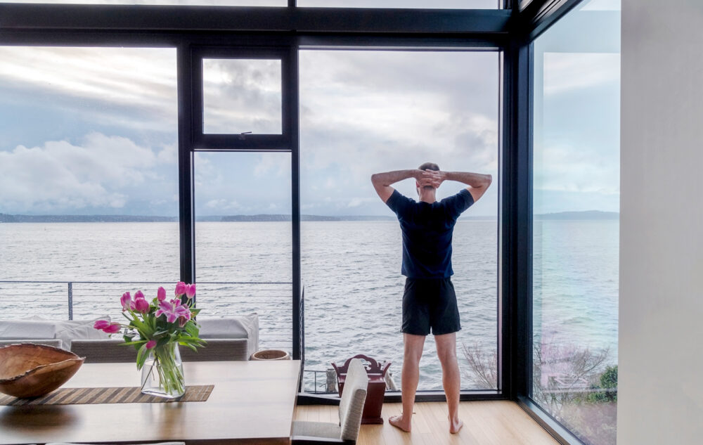 Uomo che si gode la vista mare dalla sua cucina in una casa in legno