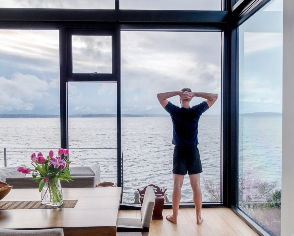 Uomo che si gode la vista mare dalla sua cucina in una casa in legno