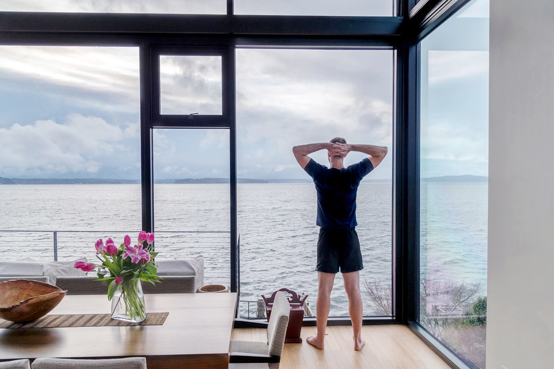 Uomo che si gode la vista mare dalla sua cucina in una casa in legno